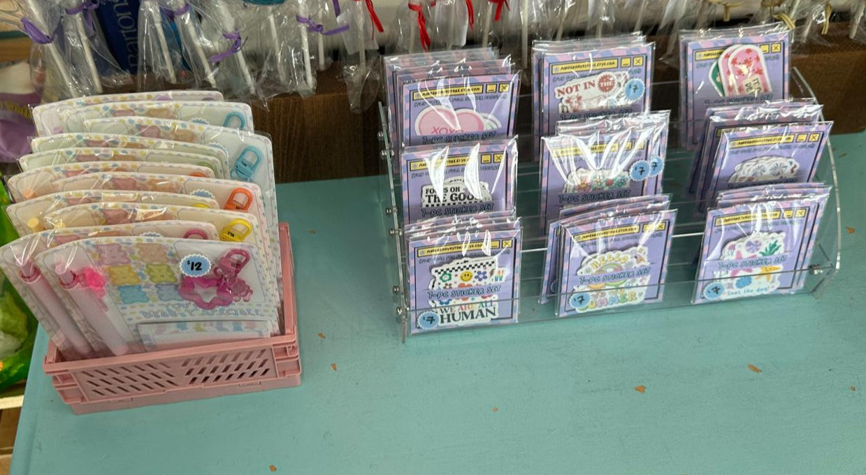 Display of colorful stickers and stationery sets on a light blue table.